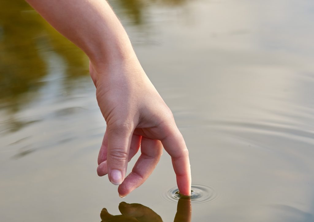 The ripple effect. Cropped shot of a finger touching water to form ripples.