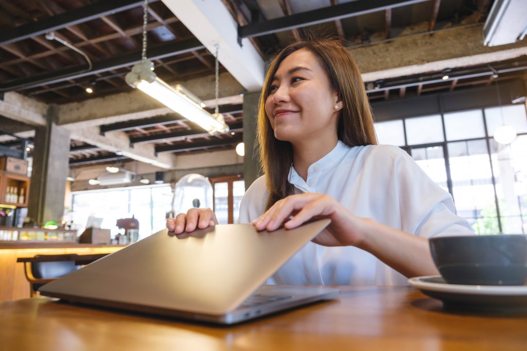 A young woman opening or closing laptop computer, getting ready